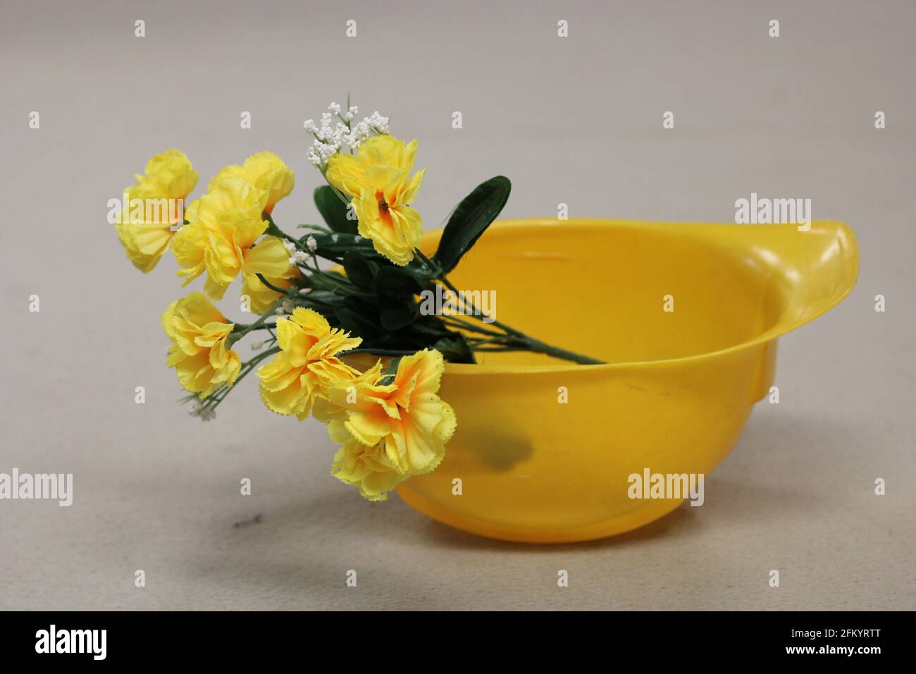 Strauß gelber Blumen, in gelbem Hut, auf braunem Hintergrund Stockfoto