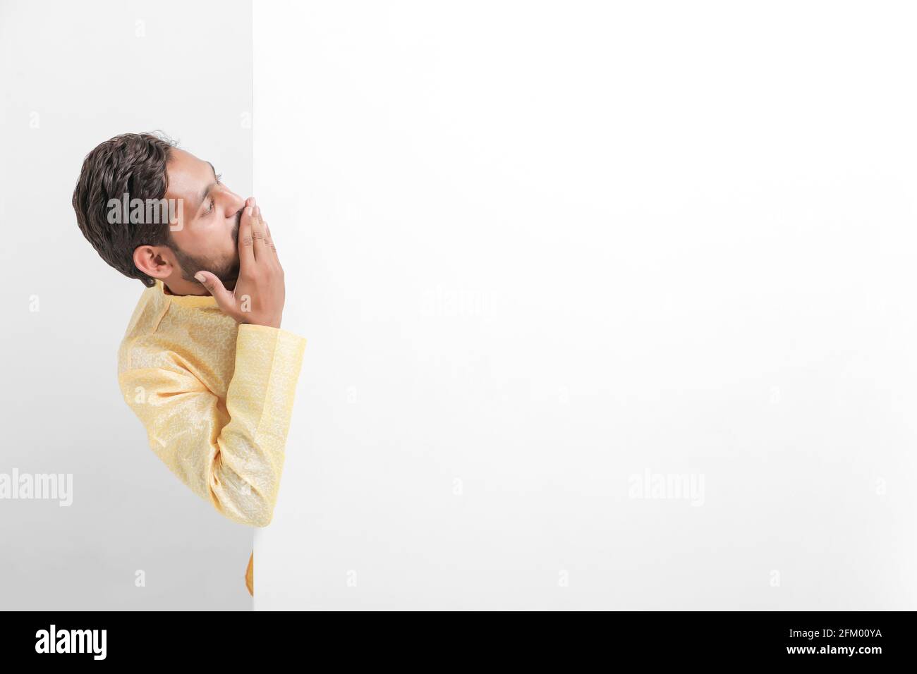 Ein indischer Mann mit Whiteboard, der während der Festivalsaison Angebote propagiert, während er traditionelle Tücher trägt und auf weißem Hintergrund steht. Stockfoto