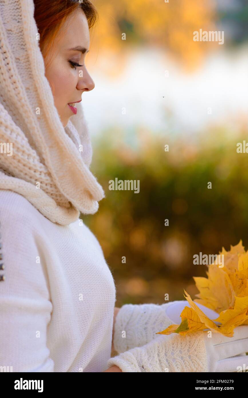 Nettes Mädchen in langen weißen Hochzeitskleid posiert in ländlichen Weg unter herbstlichen Bäumen im Wald in der goldenen Stunde. Stockfoto