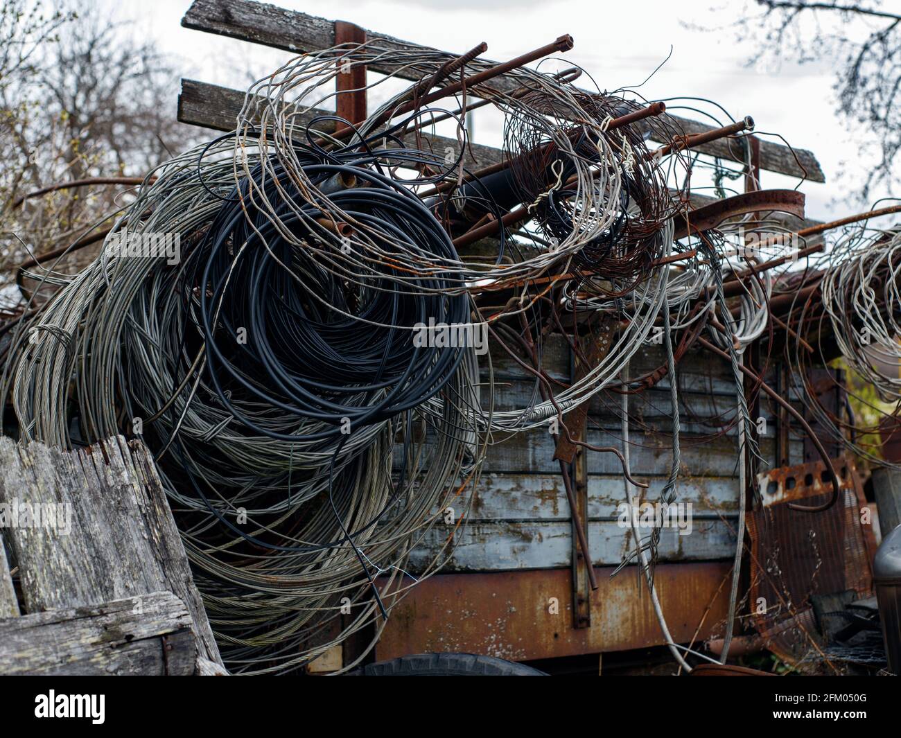 Drähte verschiedener Art werden zu Ringen verdreht und hängen an Eisenstangen. Stockfoto