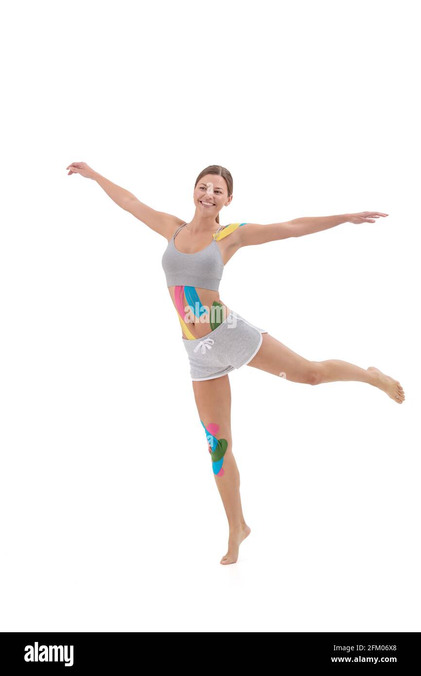 Kinesiologie-Aufnahme. Kinesiologieband auf Knie, Bauch und Schulter des Patienten. Junge Sportlerin macht Übungen. Nach traumatischer Rehabilitation, Gewicht Stockfoto
