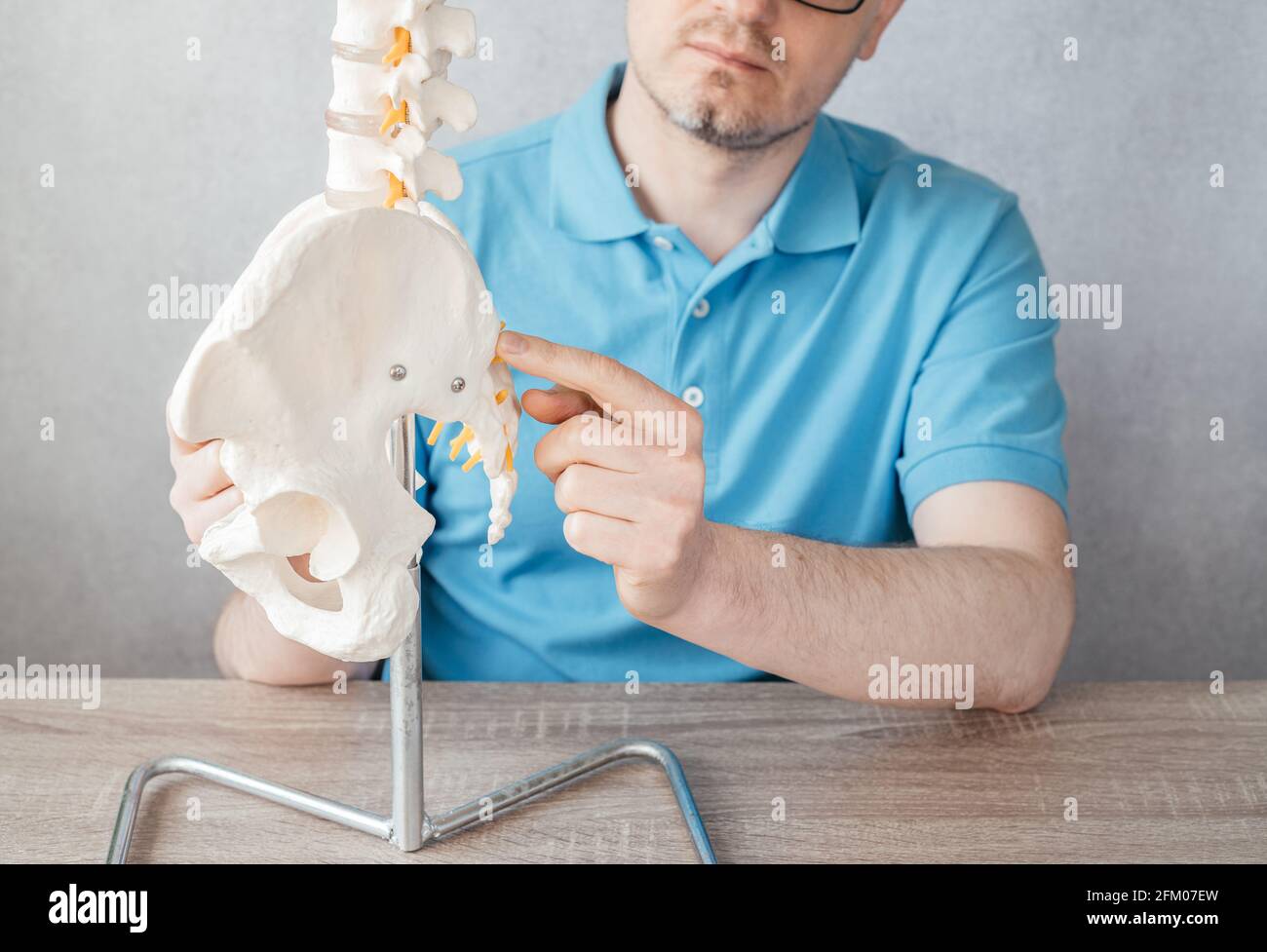 Nahaufnahme der Hand des männlichen Arztes, die auf den vorderen Vorgesetzten zeigt ASIS der Iliakalwirbelsäule auf einem Skelett-Wirbelsäulenmodell Stockfoto