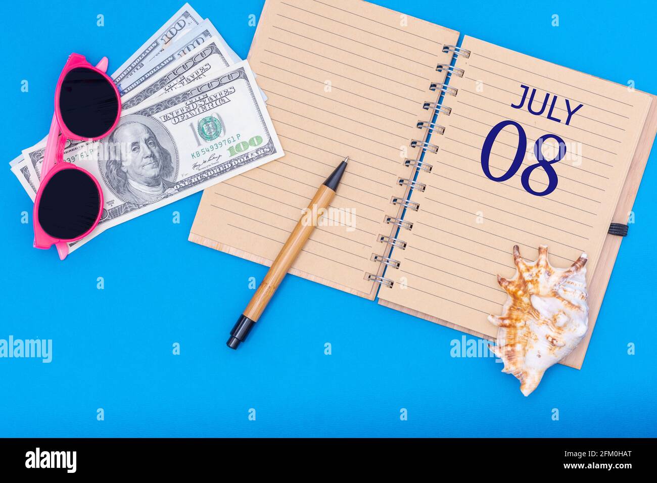 8. Tag im juli. Travel Concept Flat Lay - Notizblock mit dem Datum des 8. juli Stift, Brille, Dollar und Muschel auf blauem Hintergrund. Sommermonat, Tag von Stockfoto
