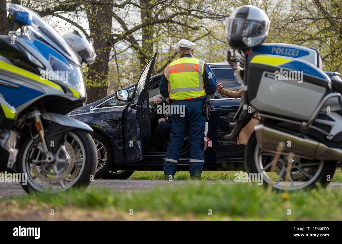 Leipzig, Deutschland. Mai 2021. Ein Polizeibeamter der Leipziger Verkehrspolizei überprüft einen Autofahrer in der Jahnallee in Leipzig. Die Kontrollen führt die Leipziger Polizei im Rahmen der bundesübergreifenden Verkehrssicherheitskampagne sicher.mobil.leben durch. Ziel ist es, die Straßenverkehrssicherheit für alle Verkehrsträger zu erhöhen, die am Straßenverkehr beteiligt sind. Quelle: Hendrik Schmidt/dpa-Zentralbild/ZB/dpa/Alamy Live News Stockfoto