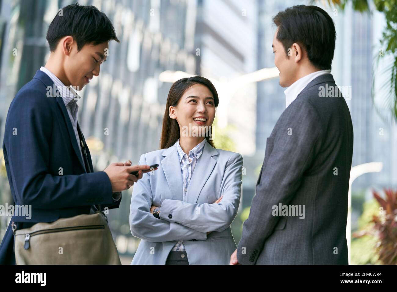 Drei asiatische Geschäftspartner plaudern in der Straße der Innenstadt Finanzviertel in der modernen Stadt Stockfoto