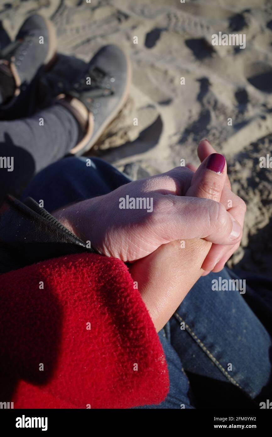 Mann und Frau mit rot gestrichenen Nägeln halten sich an einem sonnigen Sommertag am Strand von Palavas les Flots, in der Nähe von Carnon Plage, in der Nähe von Montpellier Stockfoto