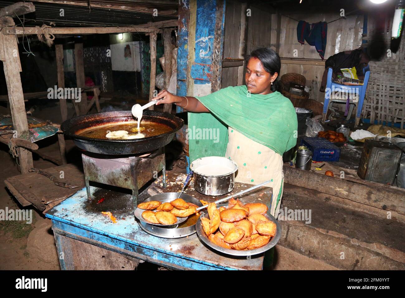 Eine junge Stammesfrau, die traditionelle Pongadam-Süßigkeiten in Araku Village, Andhra Pradesh, Indien, herstellt Stockfoto