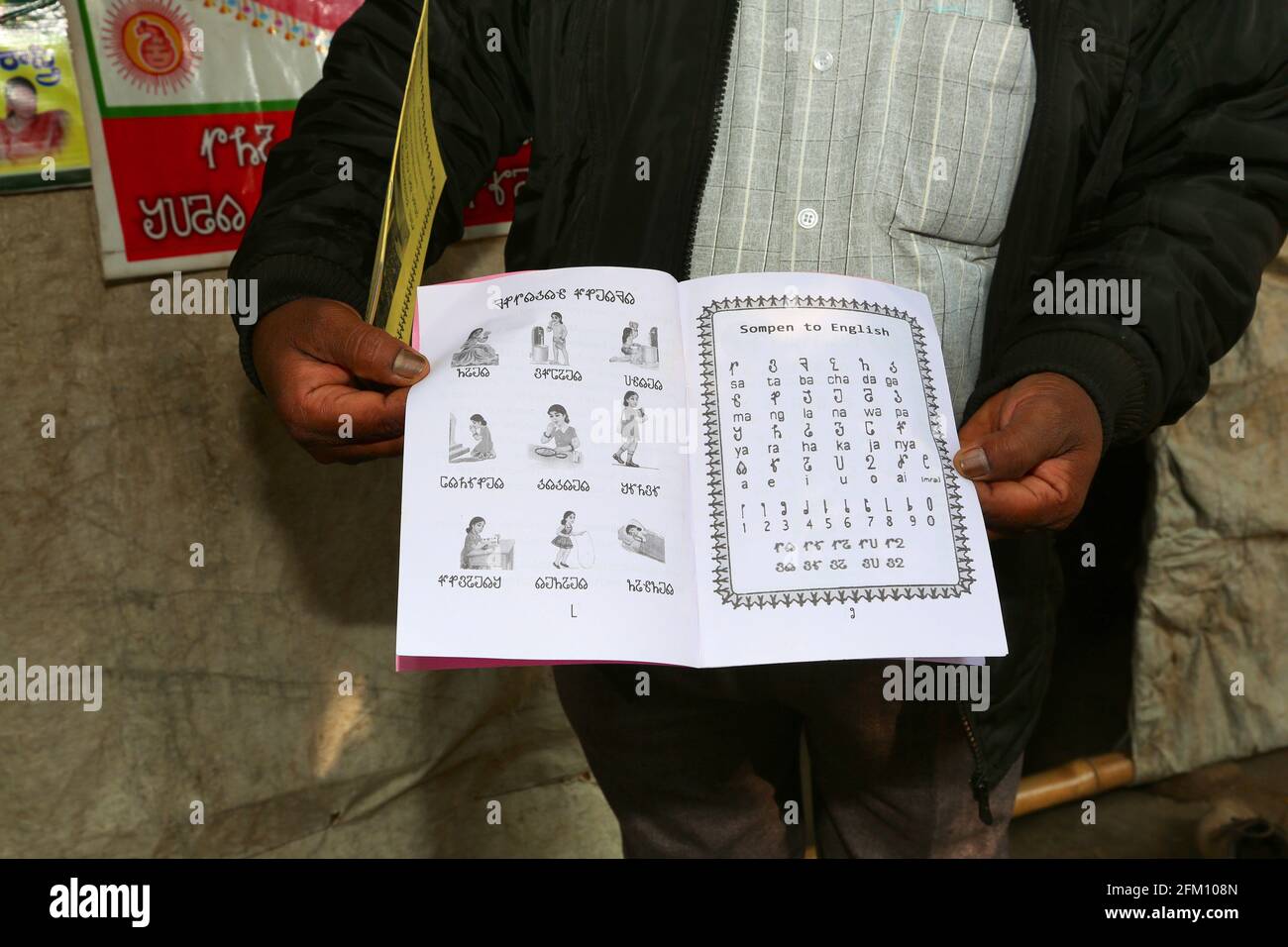 Ein Stammesmann, der im Dorf Sativada im Bezirk Srikakulam, Andhra Pradesh, Indien, ein Lehrbuch über Savara-Alphabete zeigt. SAVARA-STAMM Stockfoto