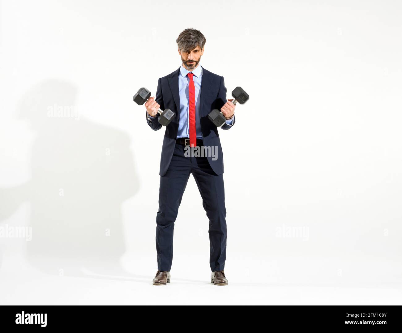 Smart Geschäftsmann im Anzug heben zwei Hanteln Gewichte, weiß Studio Hintergrund. Stockfoto