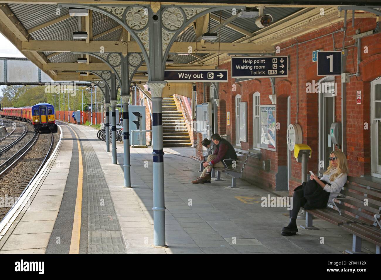 Passagiere warten auf dem Bahnsteig an den Bahnhöfen Cobham und Stoke D'Abernon, Surrey, Großbritannien Stockfoto