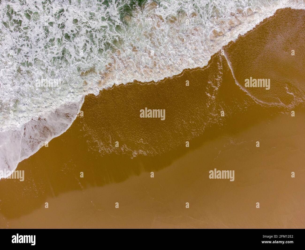 Luftdrohne Top Down View - Wellen an einem Strand Mit goldenem Sand - Sommerurlaub Stockfoto