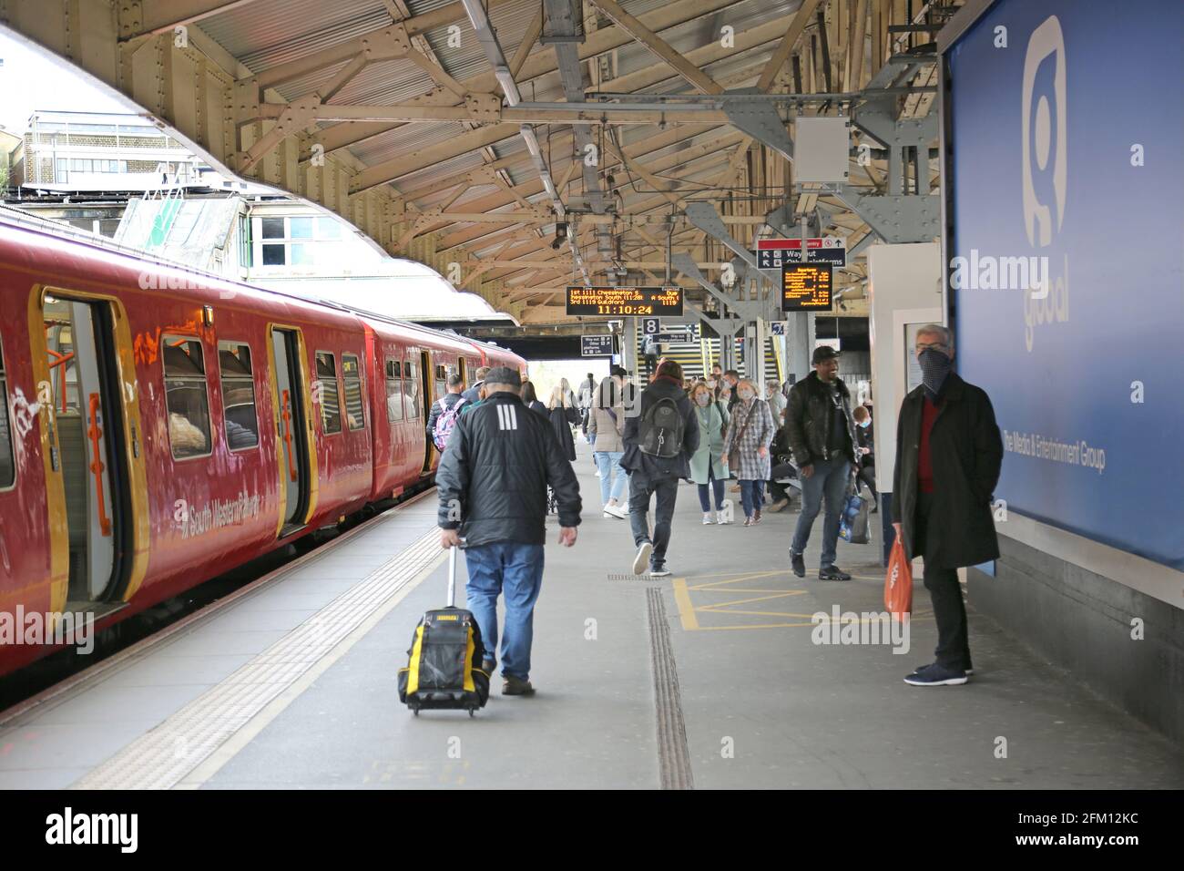 Der Bahnsteig am Bahnhof Wimbledon in London zeigt Passagiere und einen lokalen Zug der Southwestern Railways. Stockfoto