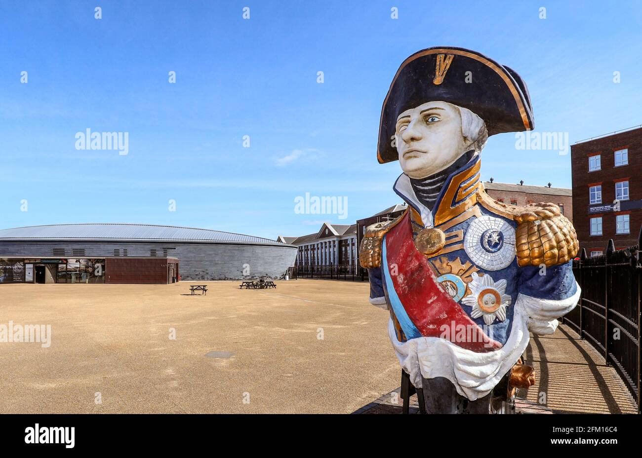 HMS Trafalgar Galionsfigur des Vizeadmiral Horatio Lord Nelson mit dem Mary Rose Museum im Hintergrund, Portsmouth Historic Dockyard, Portsmouth. Stockfoto