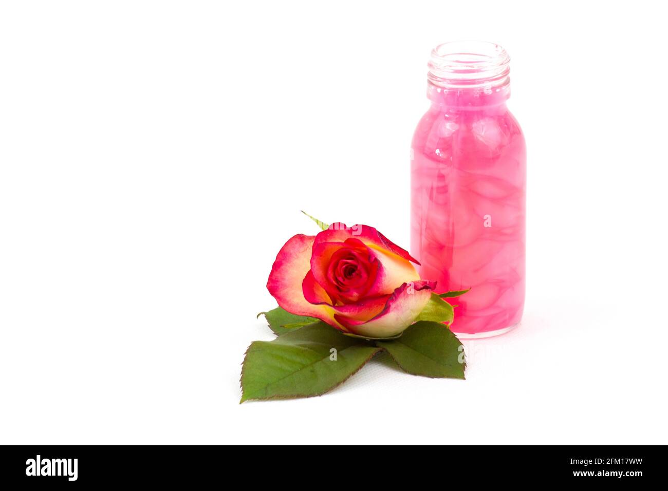 Badeöl und rosa Rosen auf weißem Hintergrund Stockfoto