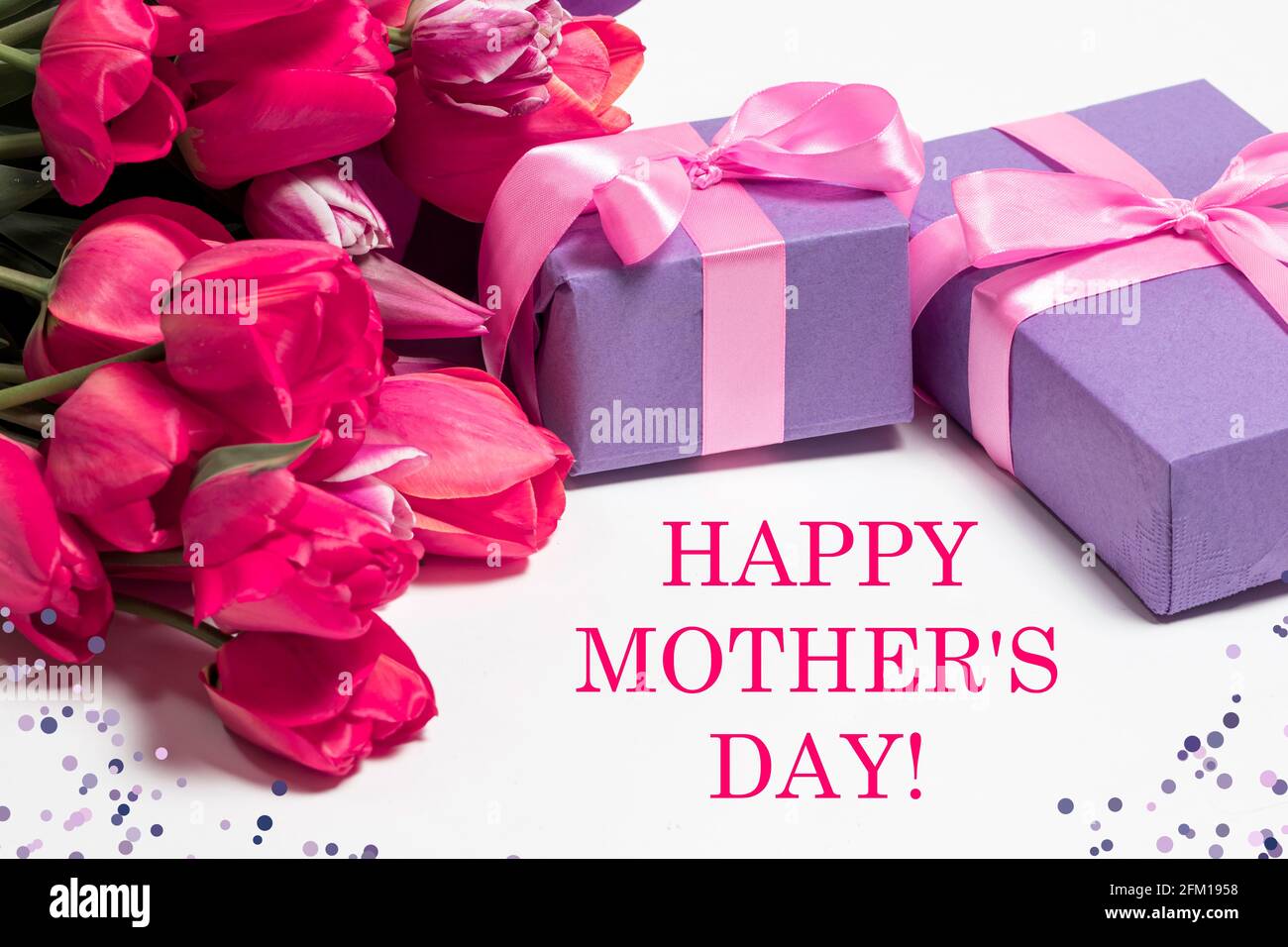 Zarte rosa Tulpen und lila Geschenkschachteln mit der Aufschrift Alles gute zum Muttertag Stockfoto