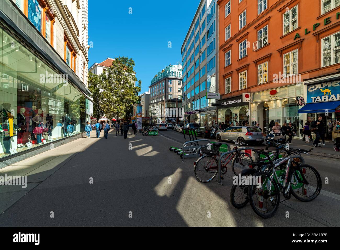 Fahrräder in der Fußgängerzone und Menschen, die zwischen Häusern und Schaufenstern im alten historischen Teil von Wien, Österreich, spazieren. Stockfoto