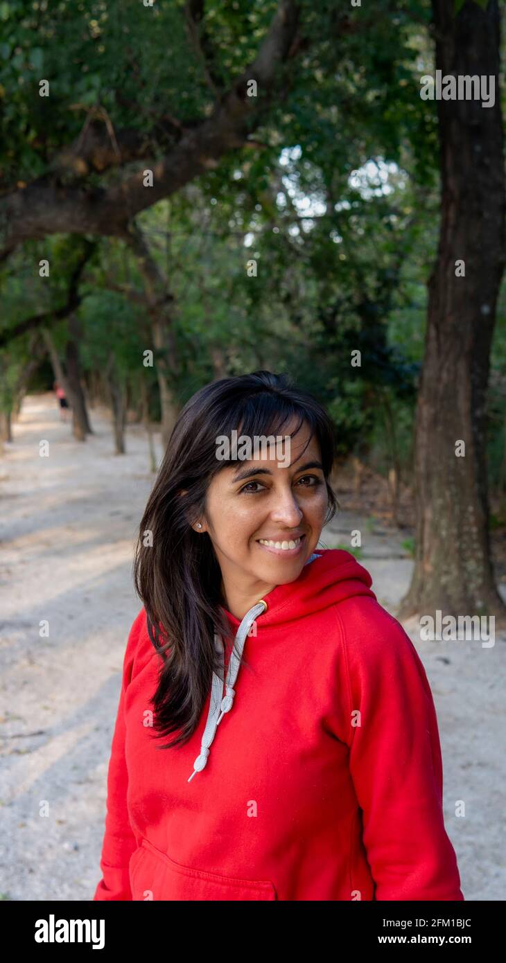 Porträt einer jungen Frau, die auf die Kamera schaut und lächelt In einem grünen Park bei Sonnenuntergang Stockfoto