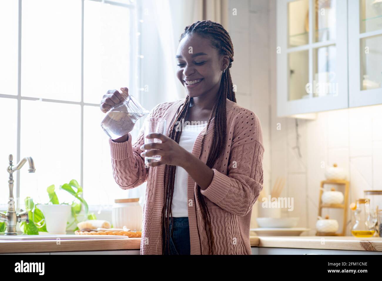 Gesundes Getränk. Happy Young African American Weiblich Trinkwasser In Der Küche Stockfoto