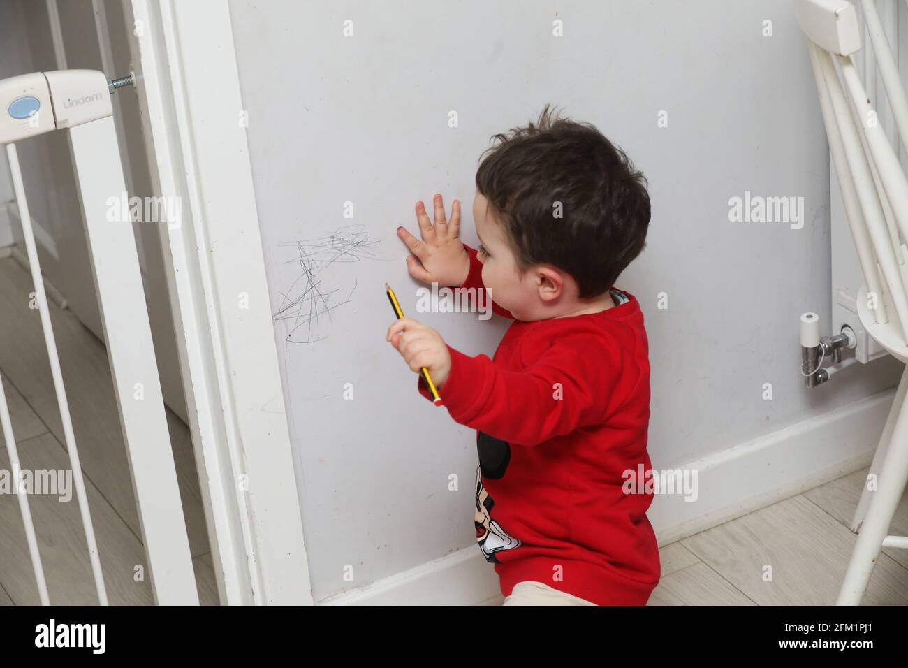 Ein kleiner Junge hat in West Sussex, Großbritannien, mit einem Bleistift an den Wänden gezeichnet. Stockfoto