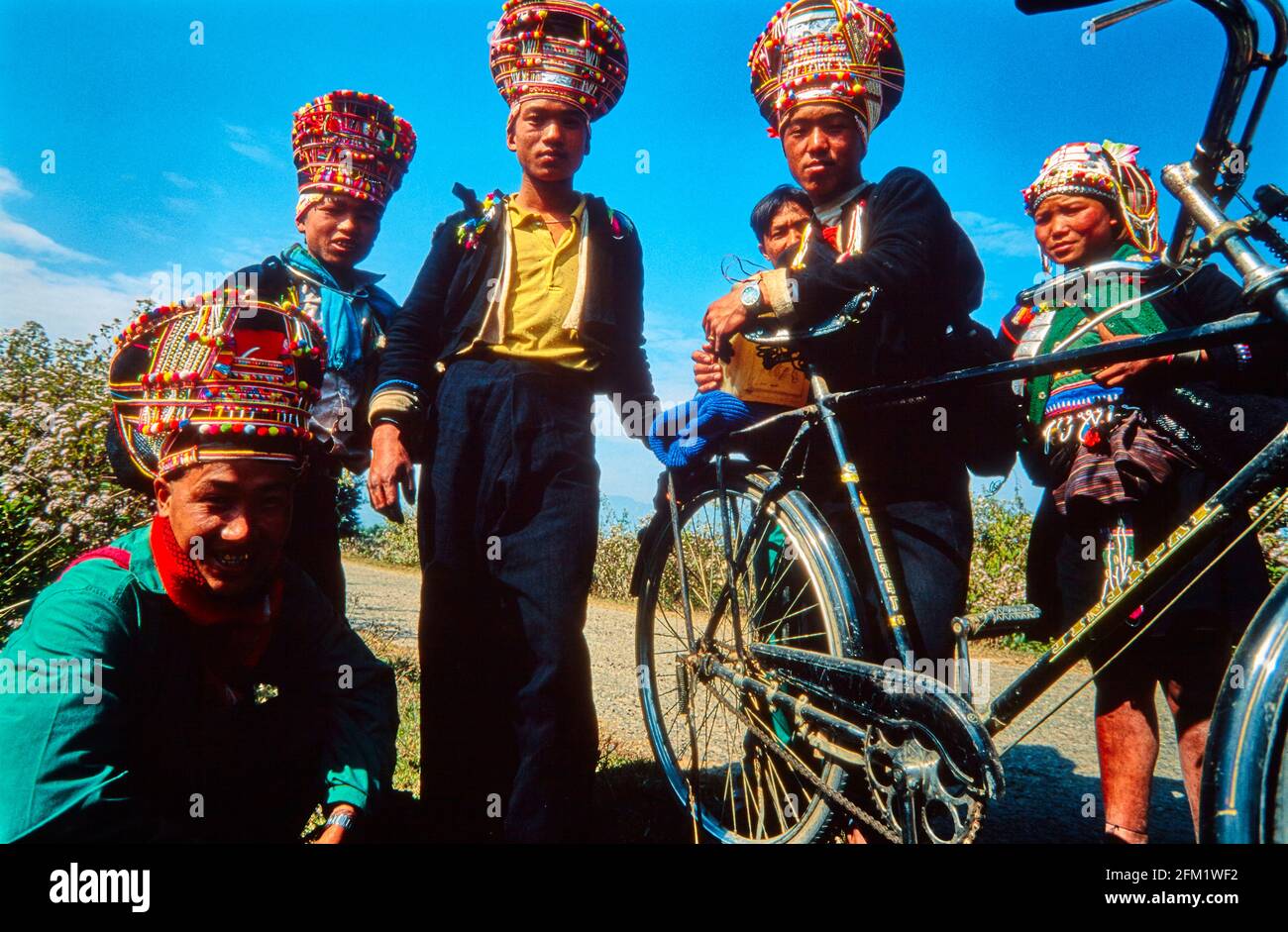 Eine Gruppe junger Männer und eine Frau aus dem Stamm der Iko mit bunten Kopfbedeckungen auf einer Straße in der Nähe von Muong Sing. 01/12997 - Christoph Keller Stockfoto