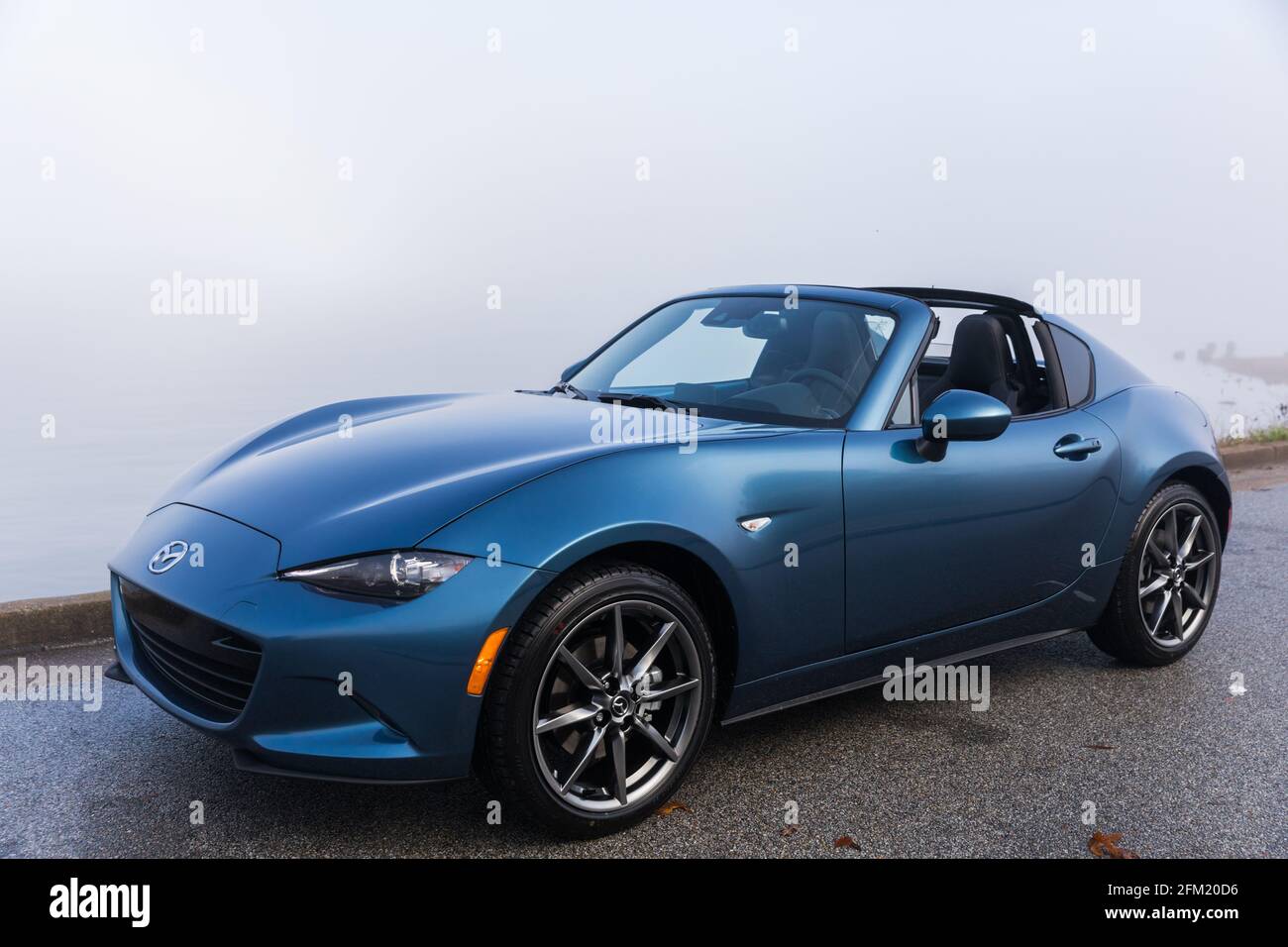 Neue blaue 2020 Mazda MX-5 GT RF, geparkt (mit dem Dach nach unten) neben dem Wasser an einem nebligen Morgen. Stockfoto