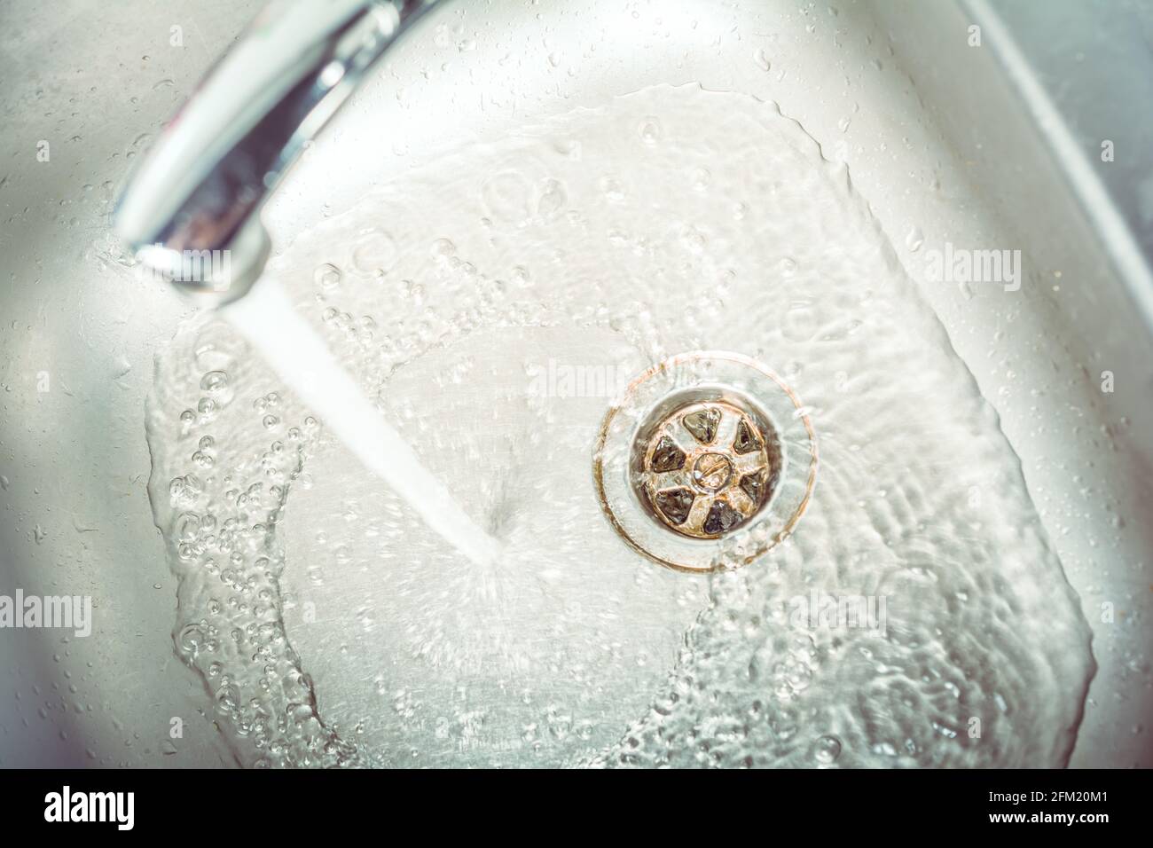 Ein Wasserstrahl, der im Waschbecken und unten am strömendes Wasser strömendes Wasser Ablassen Stockfoto