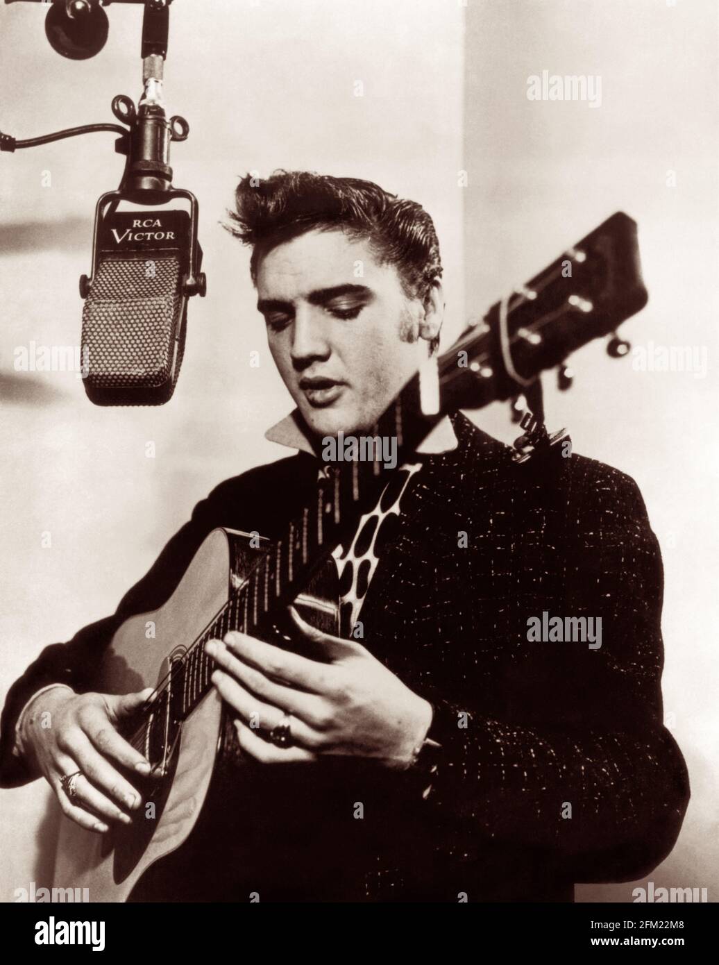 Elvis Presley im RCA Victor Studio A (aka Studio 1) in New York City am 1. Dezember 1955 mit einer geliehenen Gitarre und einem vintage RCA 44A Mikrofon. (USA) Stockfoto