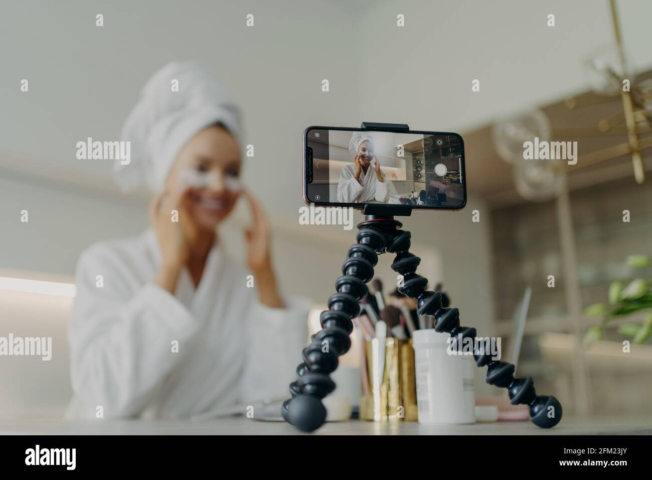 Smartphone-Bildschirm mit weiblicher Beauty-Bloggerin im Bademantel Aufnahme Video Über die Hautpflege für ihren Vlog Stockfoto