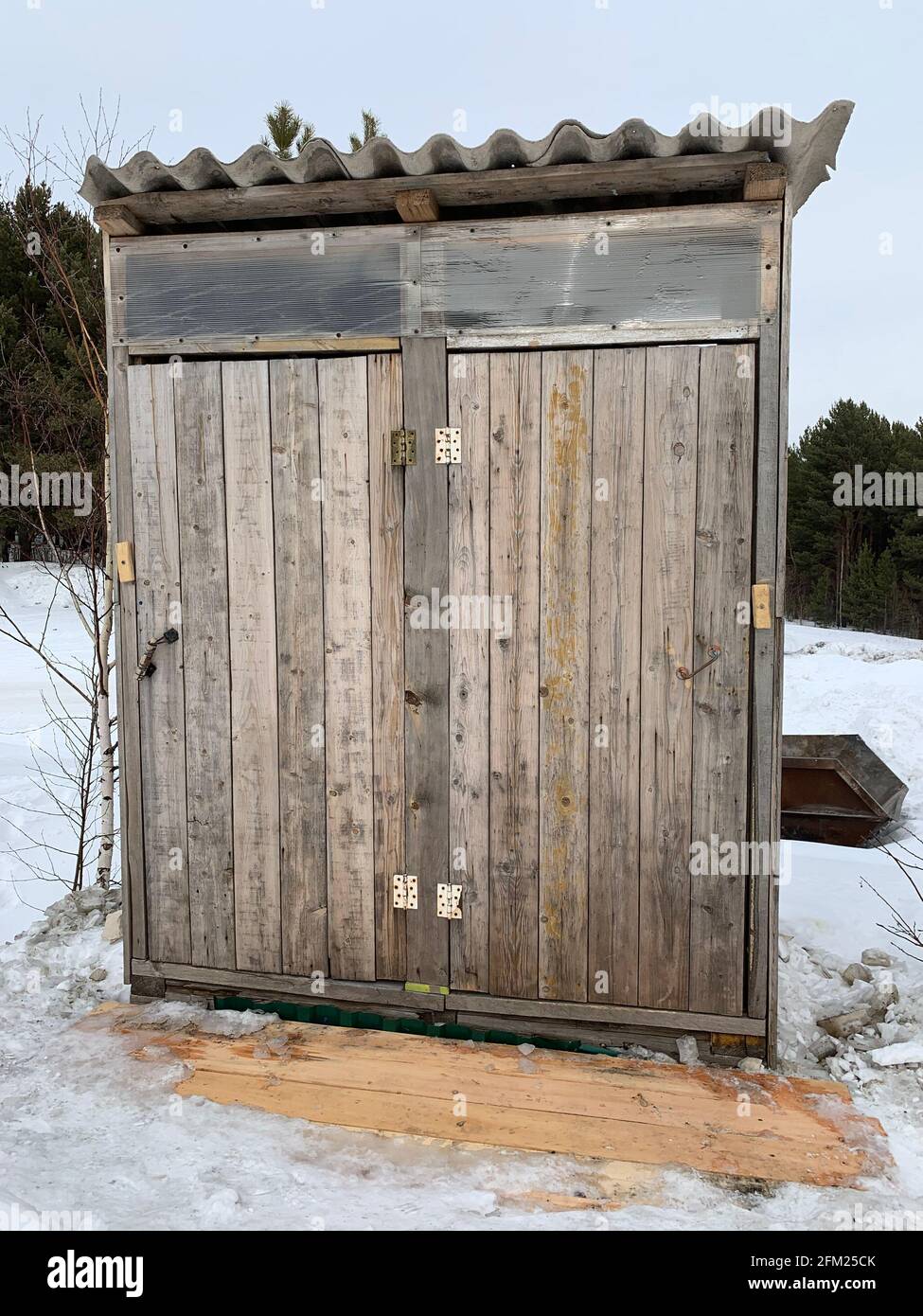 Holztoilette für zwei Personen auf dem Land im Winter, in der Natur oder einem Touristenziel. Eine alte, aber funktionierende Toilette für Leute. Stockfoto