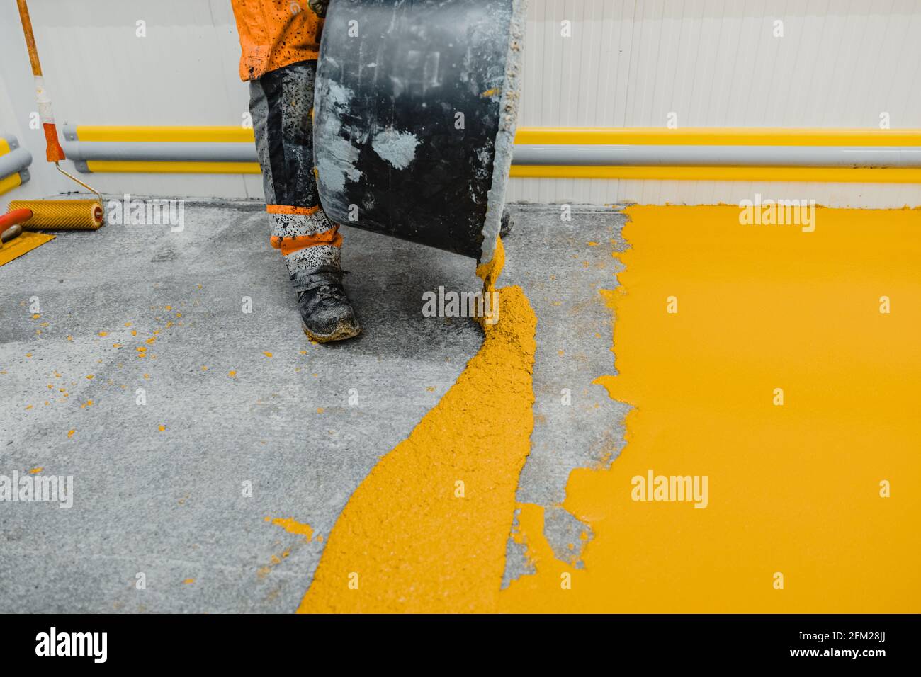 Arbeiter, der Epoxy- und Polyurethan-Fußbodensystem anwendet.Diese leicht zu reinigenden Produkte haben auch rutschfeste Eigenschaften. Stockfoto