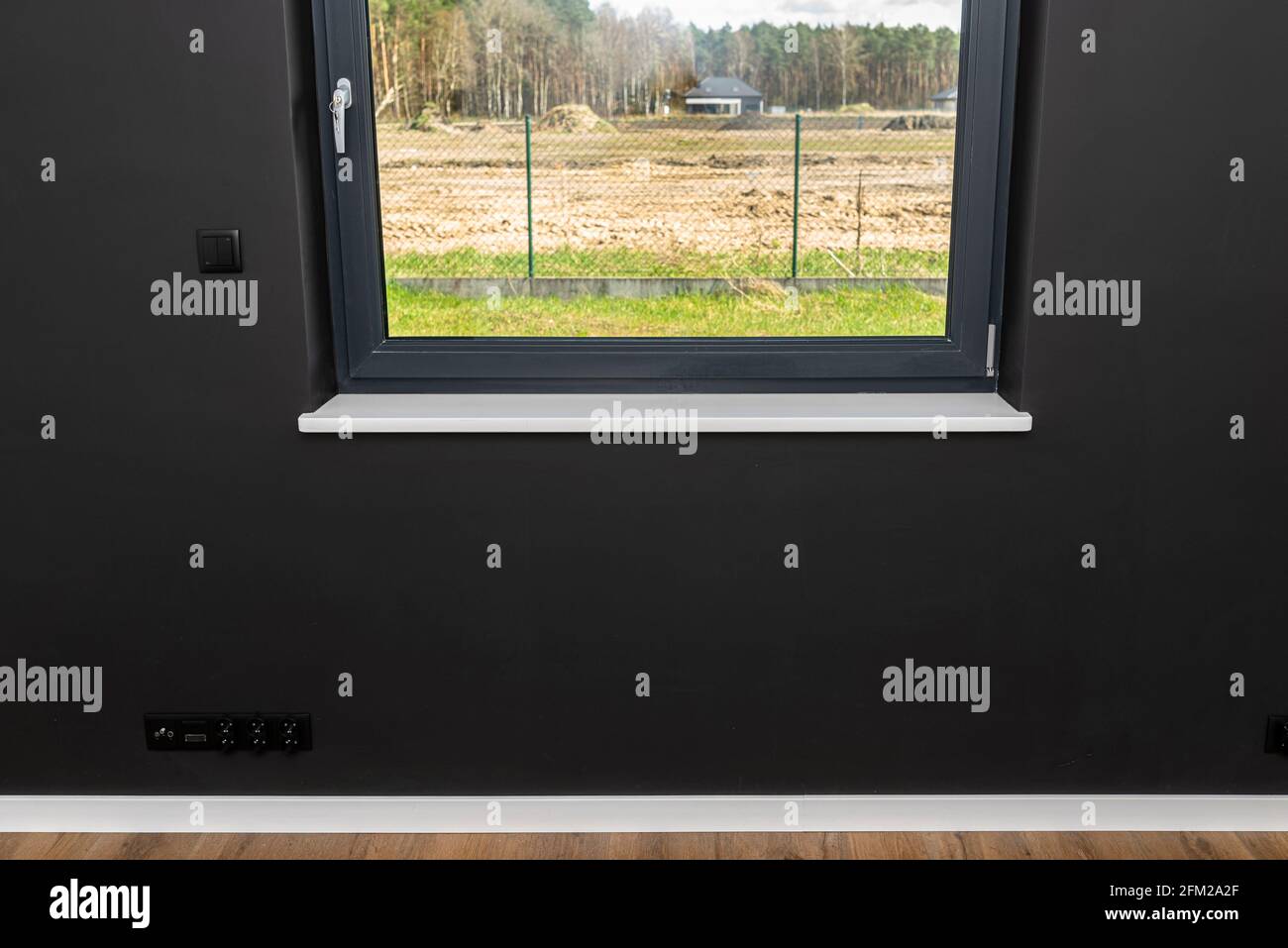 Ein großes Fenster in einem Raum mit schwarzen Wänden und vollständig geöffneten Rollläden. Stockfoto