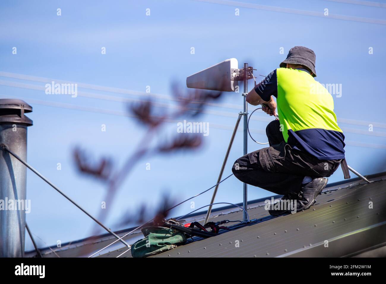 Ein mobiler Internettechniker auf dem Land installiert einen Yagi auf einem Dach, um sich mit dem Mobilfunknetz zu verbinden und den Bewohnern eine Internetverbindung zu ermöglichen, Canterbury. Stockfoto