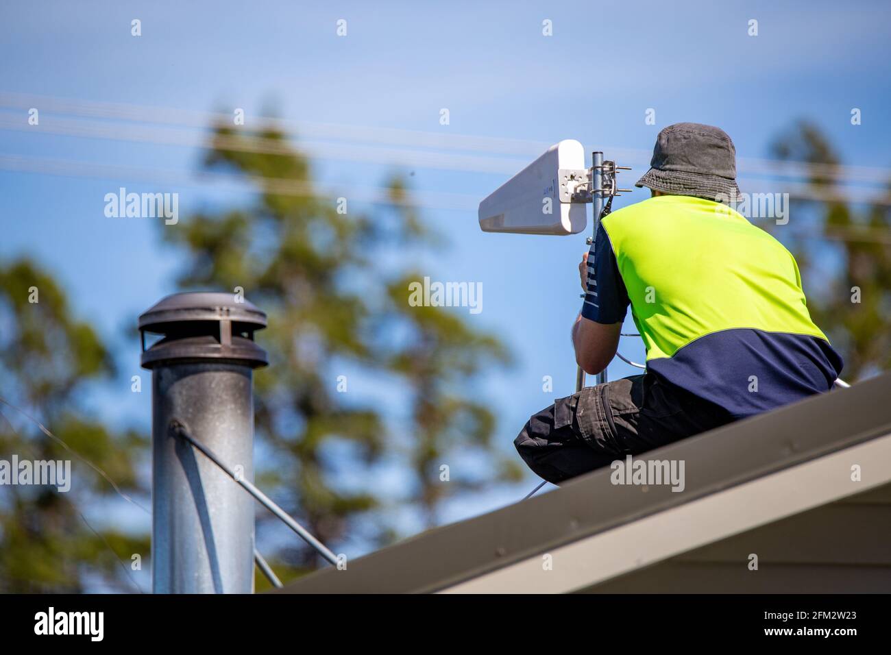 Ein mobiler Internettechniker auf dem Land installiert einen Yagi auf einem Dach, um sich mit dem Mobilfunknetz zu verbinden und den Bewohnern eine Internetverbindung zu ermöglichen, Canterbury. Stockfoto