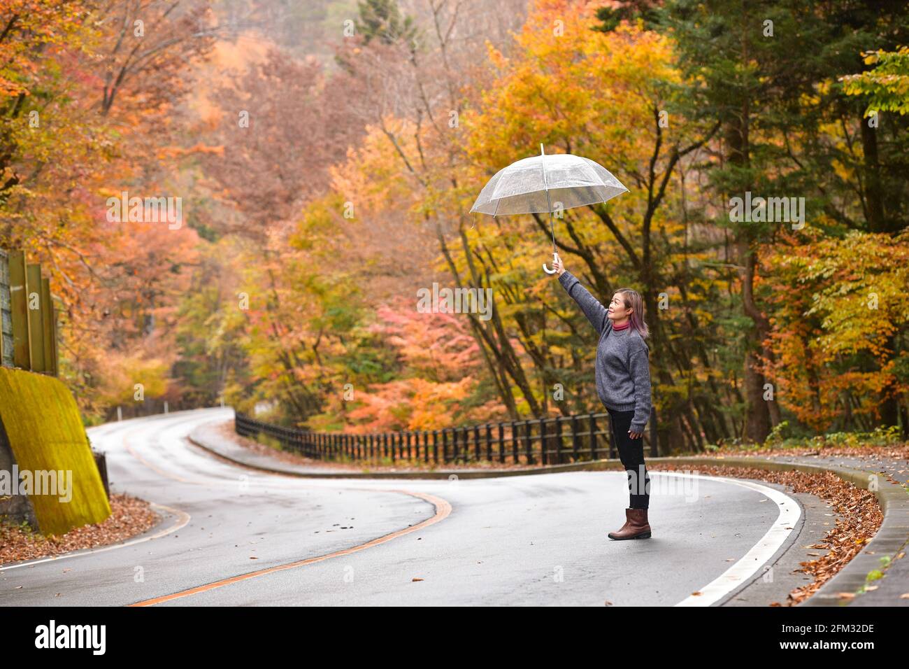 Frau, die in der Mitte der Straße mit einem Regenschirm steht, Honshu, Japan Stockfoto