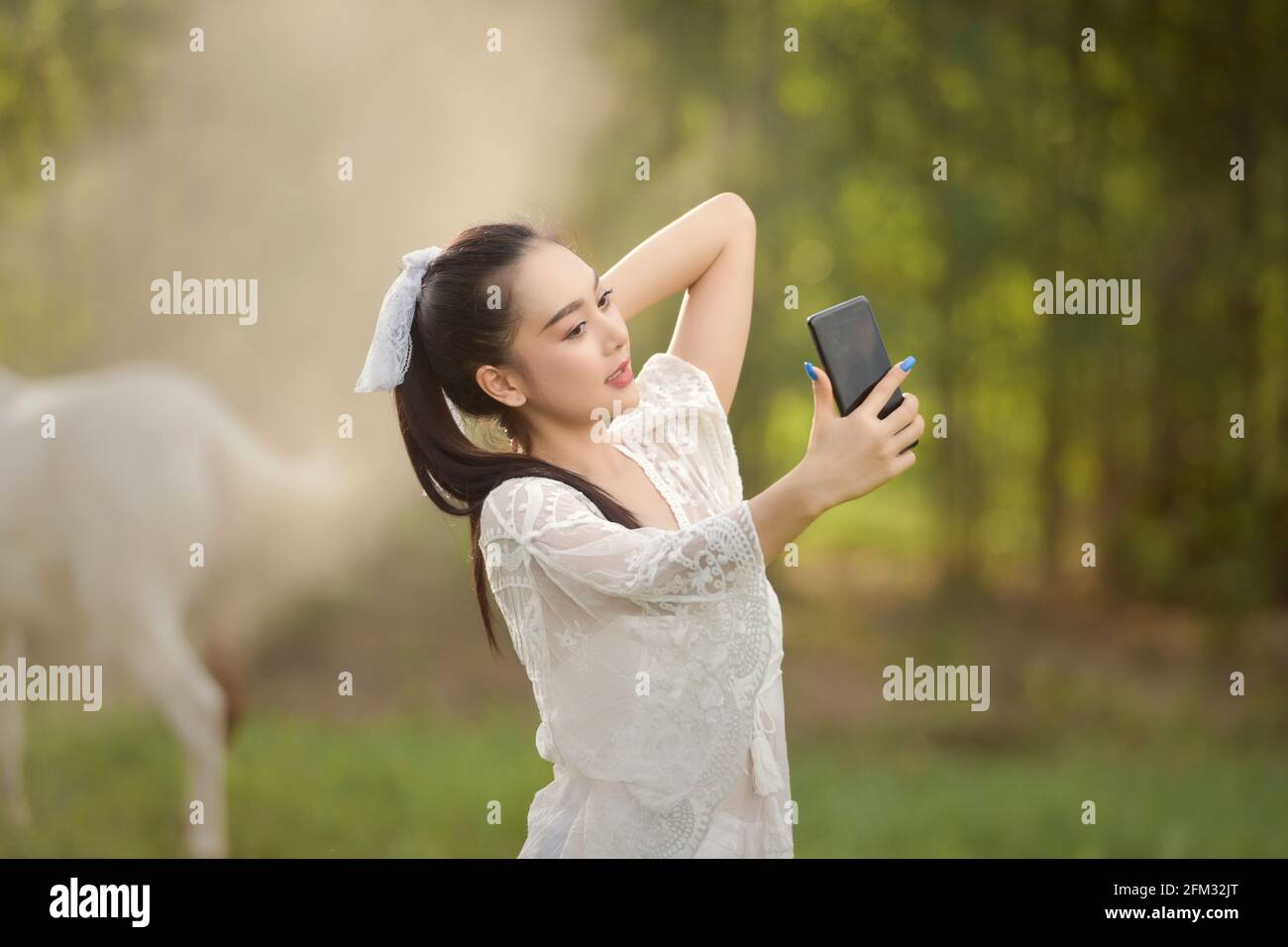 Schöne Frau, die auf einer Wiese steht und ein Selfie macht, Thailand Stockfoto