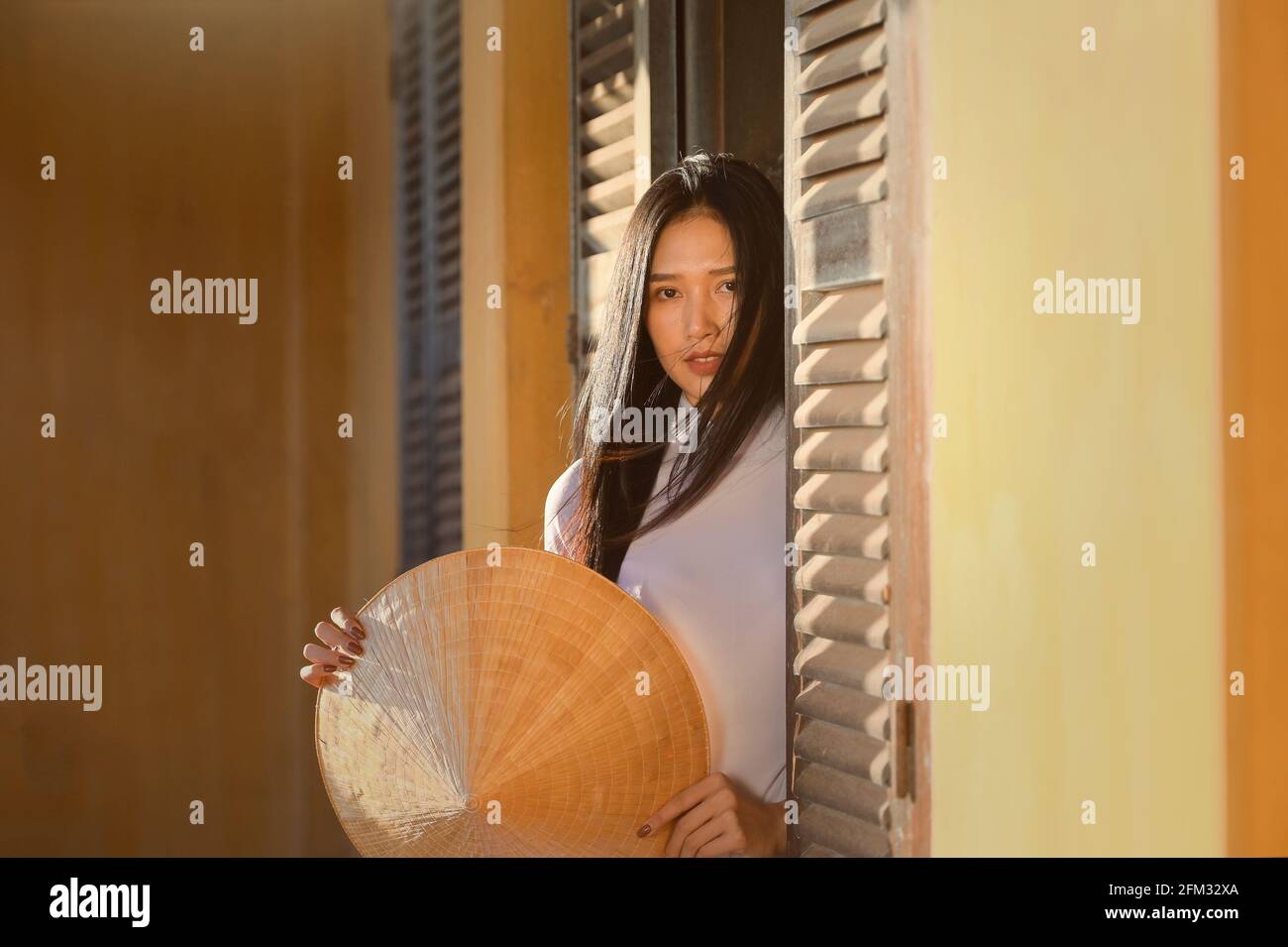 Schöne Frau, die in einer Tür mit einem traditionellen, nicht-konischen Hut steht, Thailand Stockfoto