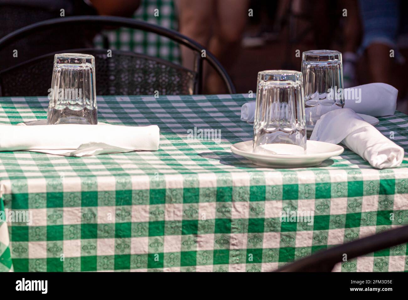 Ein Tisch im Freien in einem Restaurant zur Mittagszeit ohne Kunden in der Nähe. Glasbecher werden umgedreht auf Teller gelegt, um zu vermeiden, dass Staub einkommt. Besteck ist vorhanden Stockfoto