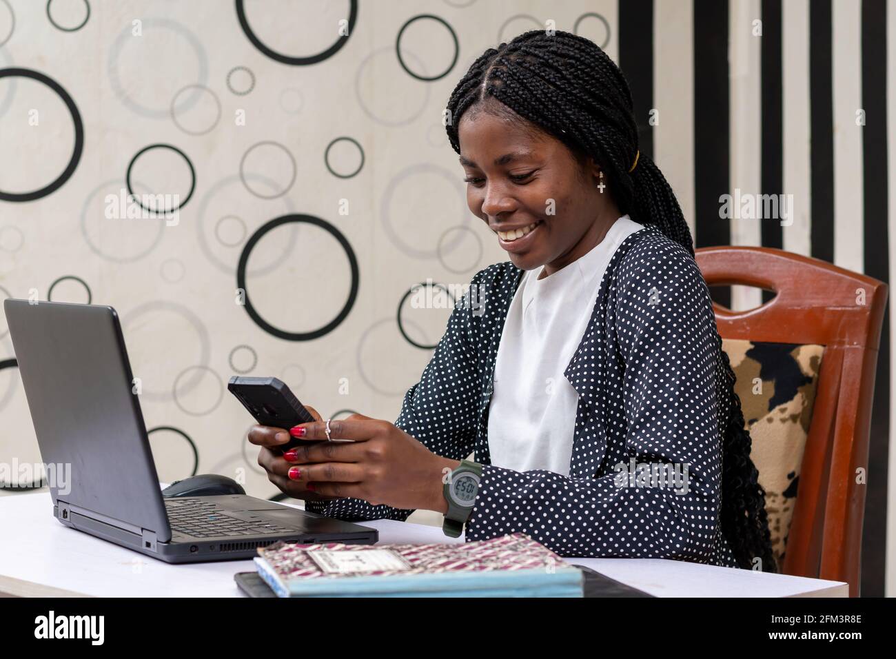 Glückliche afrikanische Frau, die ihren Freunden SMS schreibt, um gute Nachrichten zu liefern Einen Job zu bekommen Stockfoto