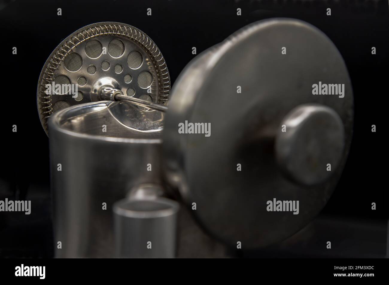 Die Nahaufnahme des Kaffeekolbens von Cafetiere wird auf eine Edelstahlkanne mit geringer Schärfentiefe auf schwarzem Hintergrund platziert.French Press Coffee. Abstraktes Metallw Stockfoto