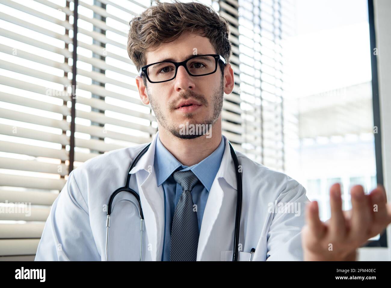 Junger männlicher Arzt, der die Kamera anschaut und mit ihm spricht Patient online per Videoanruf für medizinische Fernberatung Telemedizinische CO Stockfoto