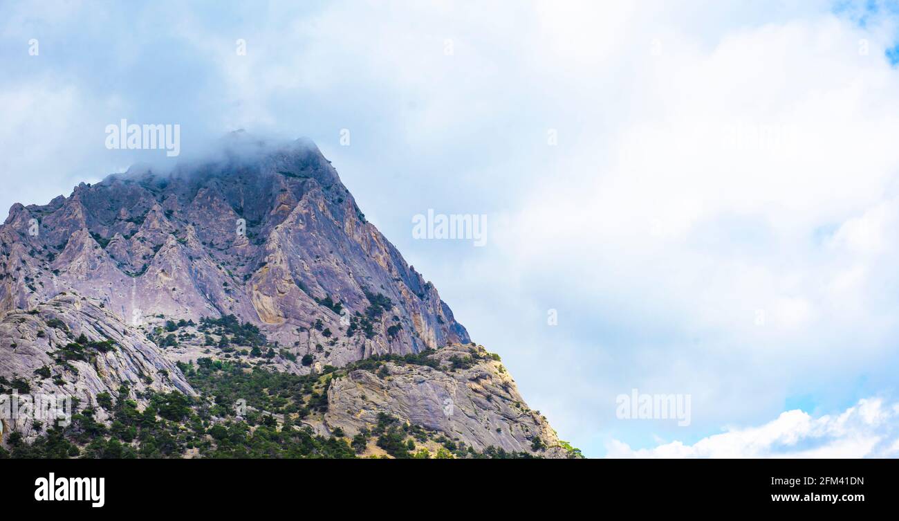 Berg in den Wolken. Wolkiger Himmel und hohe Klippen. Stockfoto