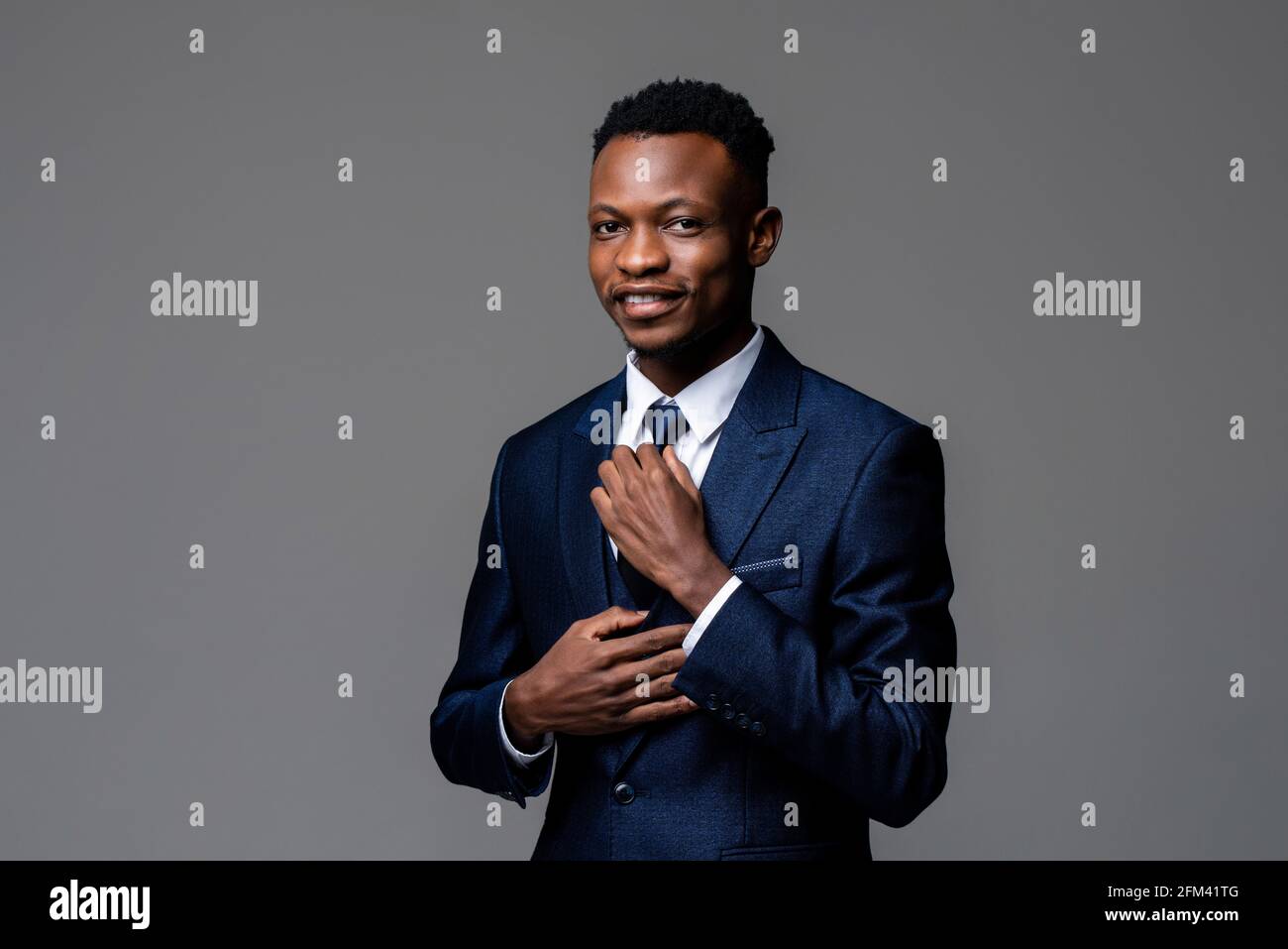 Porträt eines jungen hübschen afrikanischen Mannes in formellem Business-Anzug Mit Krawatte und Blick auf die Kamera isoliert auf Studio grau Hintergrund Stockfoto