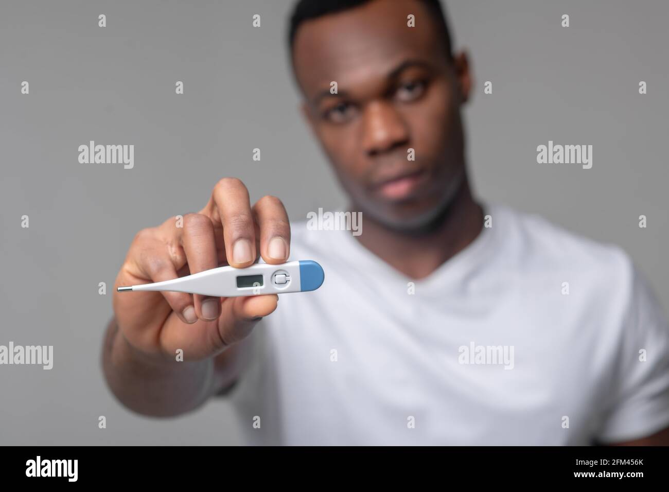 Mann hält Thermometer an die Kamera Stockfoto