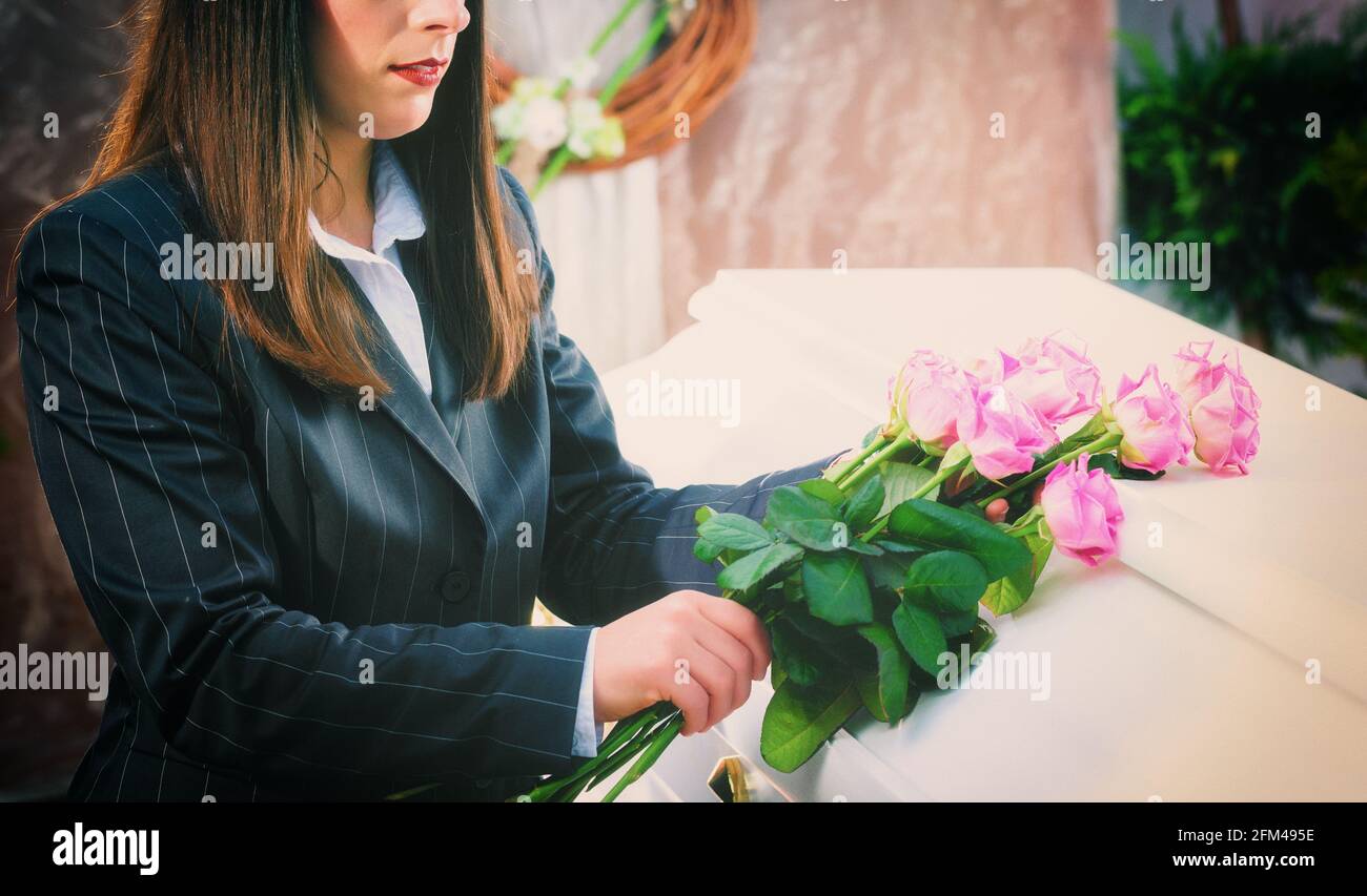 Frau, Rose auf Sarg am Begräbnis Stockfoto