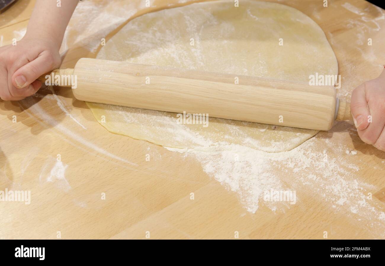 Die Hände des Kochs Rollen den dünnen Teig aus. Konzept der Pizza oder Backen Stockfoto