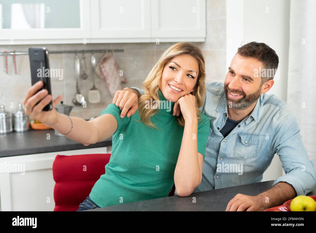 Glückliches Paar macht ein Selfie in der Küche. Blonde Frau macht ein Foto mit ihrem Freund. Smartphone, Glück und Lifestyle zu Hause. Stockfoto