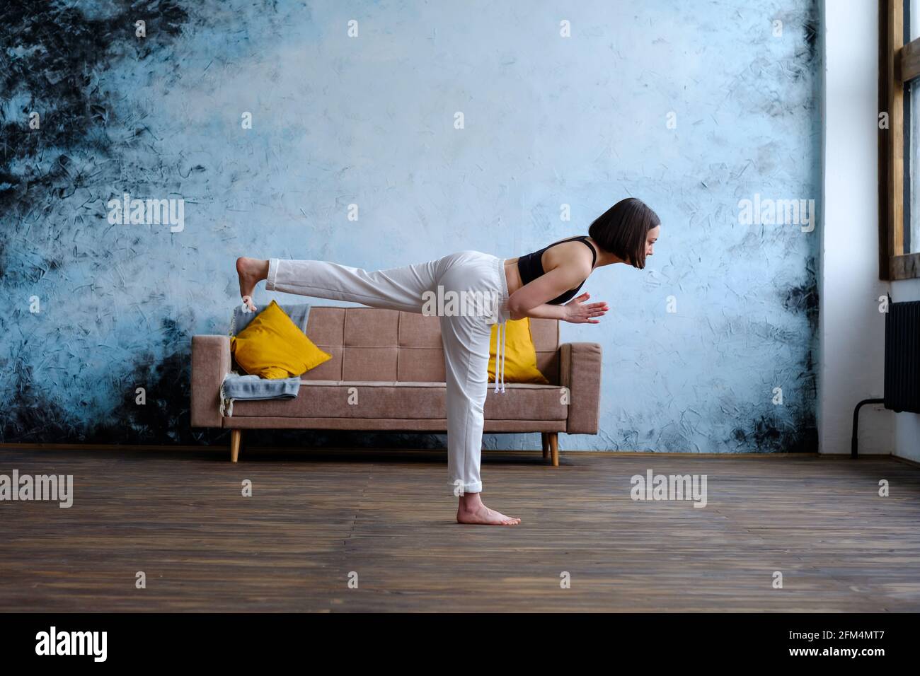 Schöne Frau, die Yoga zu Hause macht, Virabhadrasana III, Krieger Pose III Stockfoto