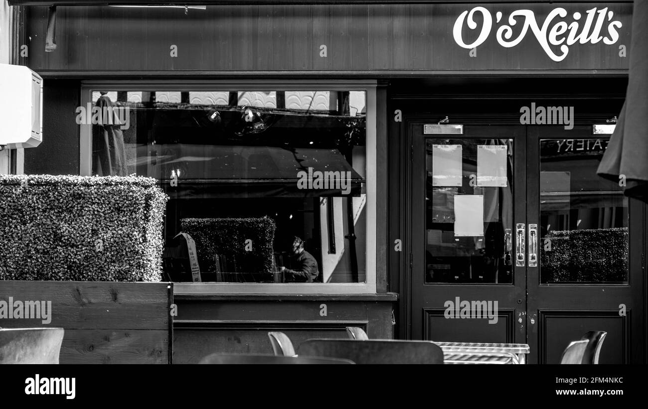 Kingston upon Thames London, Großbritannien, 04 2021. Mai, Black and White Image der Mensch, der im Fenster EINER Bar oder Kneipe isst Stockfoto