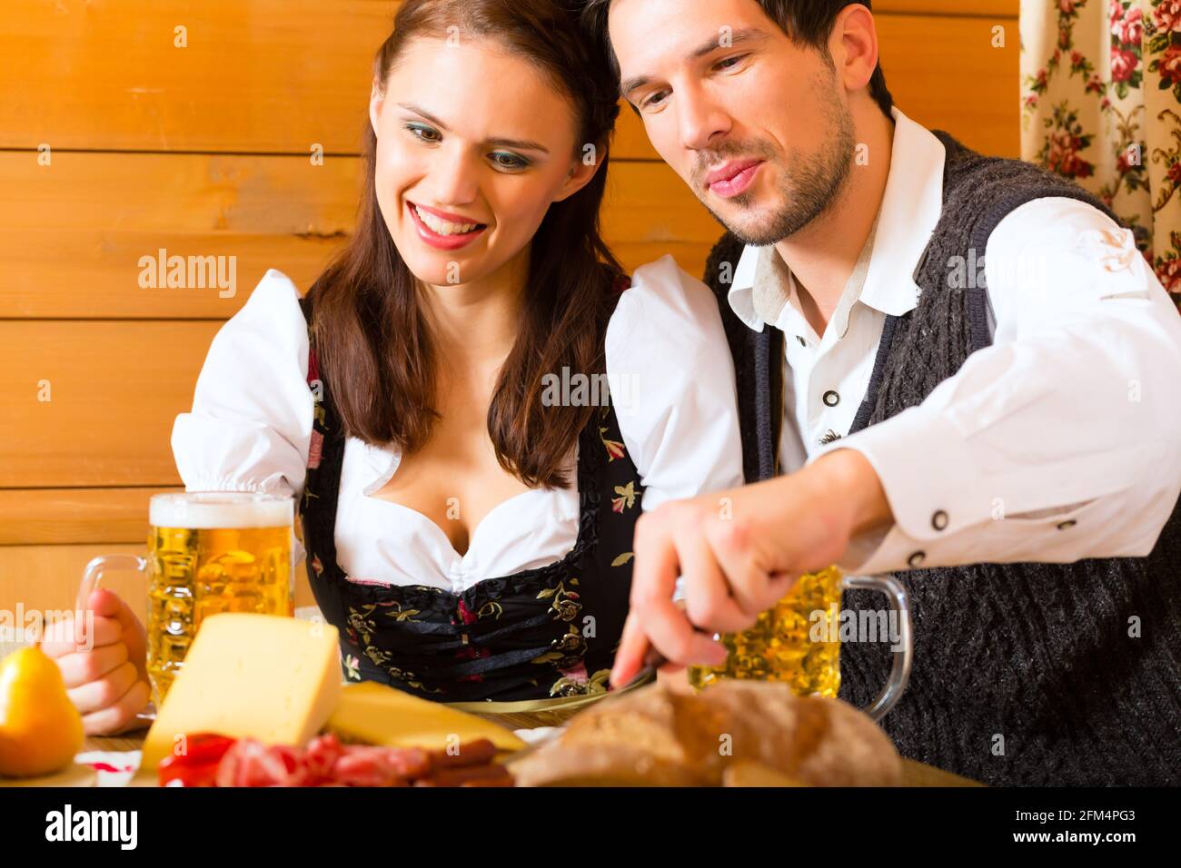 Paar in einem traditionellen Berg Hütte mit einer Mahlzeit mit Brot und Aufschnitt Stockfoto