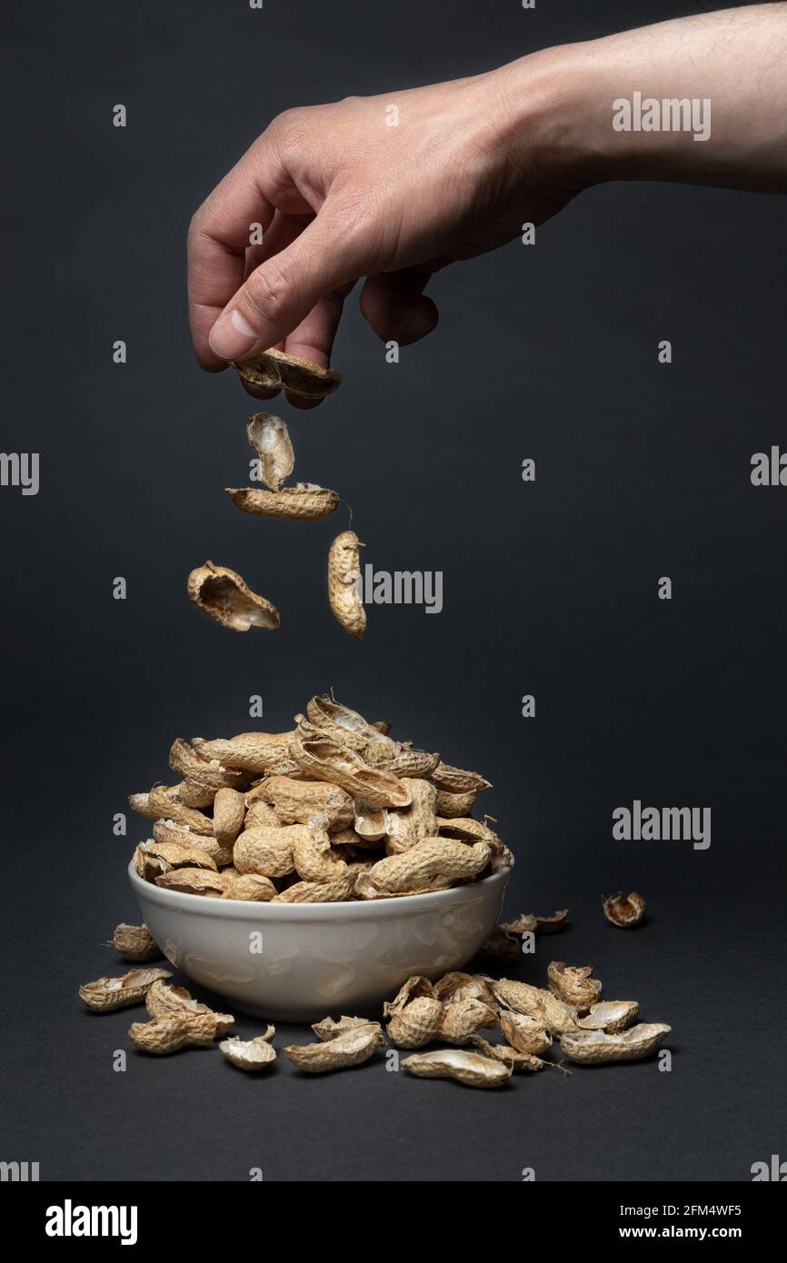 Menschenhand, die Erdnussschalen in eine Schüssel wirft Stockfoto